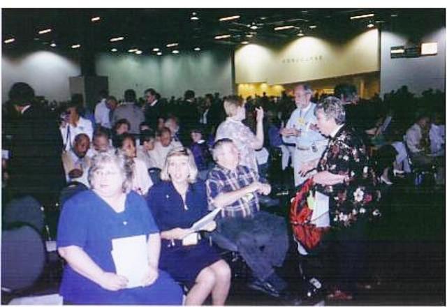 a group representing ECD chats in ASL in front row of a large assembly in a big convention center room