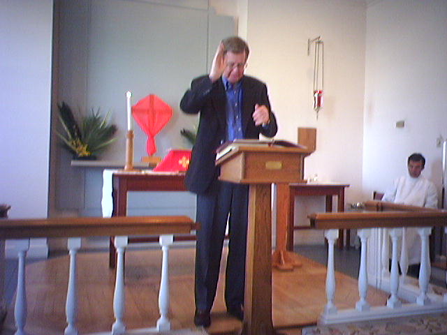 Ron Sutcliffe reads a lesson.  It looks like he is making the sign for "God"