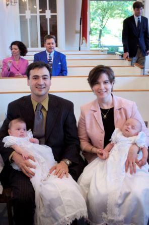 Derek and Tonya sitting in front pew each holding a twin in white Christening gowns.   One baby is asleep and the other looks happy.   The congregation is dressed a bit more formally than usual.  Nice picture courtesy of the family.