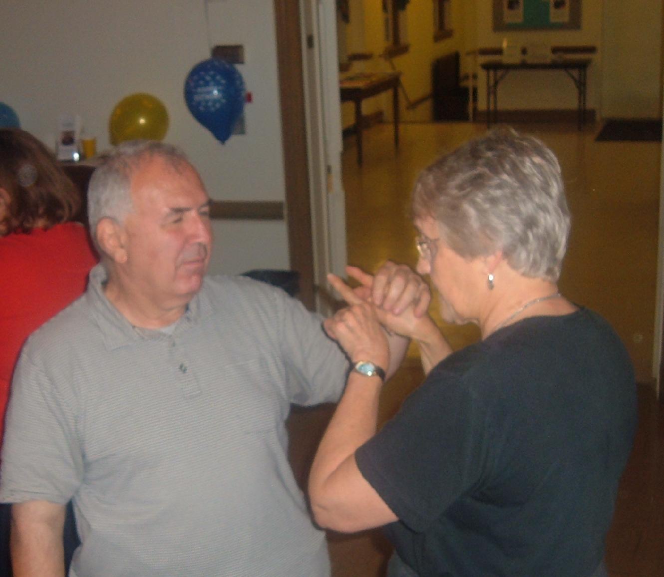 Ron Farris chatting with the Rev. Barbara Allen at Ron's birthday party in Parish Hall.   They are using ASL in tactile mode because Ron is deafblind.  Ron is Anglican originally from Canada and he also went to school in England.