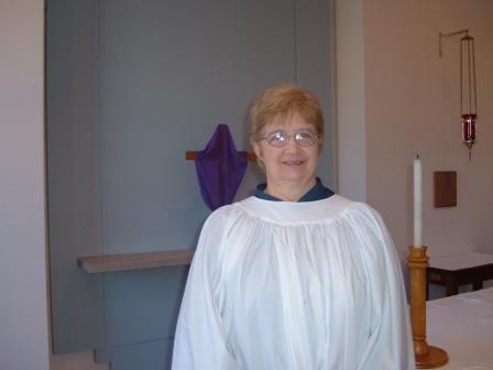 Ginny Lindsay dressed in cassock and surplice, with altar stripped for Lent