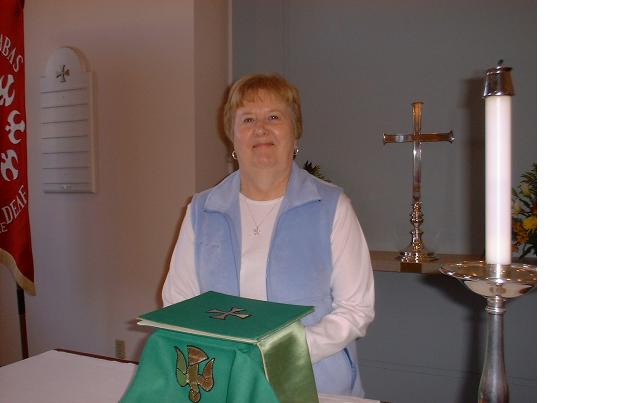 Marlene Hines pauses from setting up the altar for Holy Eucharist to smile for camera